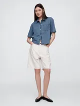 Camisa de jean de corte recto y largo a la cintura, con cuello clásico, cierre frontal de botones y un bolsillo aplicado en el pecho.