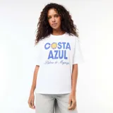 Remera oversize blanca de manga corta, con estampa frontal en tonos azules y amarillos con el texto "COSTA AZUL Palma de Majorque".