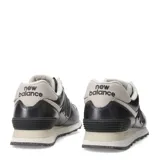 Championes urbanos New Balance modelo 574, color gris oscuro metalizado con detalles en beige claro. Presentan el logo 'N' en negro con borde blanco y cordones beige.