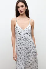 Vestido largo de color crudo con estampado de lunares negros, escote en V y tirantes finos.