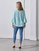 Blusa color celeste con escote en V, mangas largas acampanadas con detalle de crochet y frunces en los hombros.