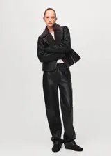Chaqueta estilo aviador de cuero sintético negro, con interior y solapas de pelo sintético gris oscuro, cierre frontal cruzado con cremallera y bolsillos laterales.