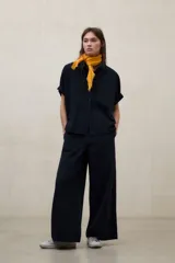 Camisa negra de manga corta con tejido de textura seersucker, corte oversize, cuello camisero y cierre frontal con botones.