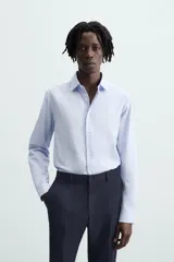 Camisa de corte regular fit en color celeste, con cuello italiano, manga larga con puños abotonados y cierre frontal de botones.