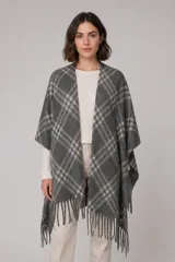 Ruana de tejido suave con diseño de cuadros en tonos gris y crema, terminada con flecos en el ruedo.