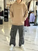 Canguro oversize tostado con capucha y bolsillo tipo canguro, confeccionado con diseño holgado. En la espalda presenta un estampado en color blanco con las palabras "FOCUS FUTURE", gráficos de estrellas y un diseño de globo terráqueo acompañado del texto "EST. 2021".