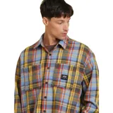 Camisa de manga larga a cuadros en tonos azul, amarillo, rojo y gris. Tiene dos bolsillos con solapa en el pecho y un logo pequeño en uno de ellos.