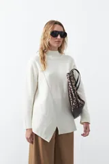 Polera de tejido de punto color marrón, con diseño asimétrico y costura diagonal frontal. Presenta cuello alto, hombros caídos, mangas largas con puños acanalados y ruedo con abertura frontal.