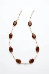 Correa para lentes con cadena color beige y abalorios ovalados con efecto carey en tonos marrones, intercalados con cuentas metálicas doradas y terminales de ajuste de silicona.