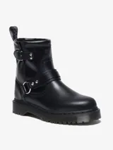 Bota biker Dr. Martens Anistone Harness, color negro, confeccionada en cuero Orleans. Presenta correas con hebillas y herrajes en plata envejecida, incluyendo una argolla metálica en el lateral. Cuenta con tirador con logo en la parte trasera y suela Bex ligeramente elevada.