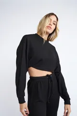 Buzo corto de tejido rib en color verde militar, con mangas largas y cuello redondo. Presenta un diseño holgado y cropped.