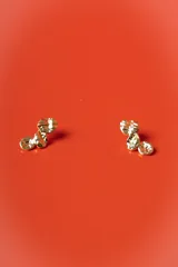 Aros de diseño orgánico con acabado metálico brillante y textura irregular, compuestos por tres piezas circulares de diferentes tamaños conectadas entre sí.