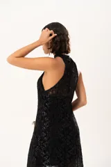 Vestido largo de encaje negro con destellos de lurex, diseño de cuello halter y tajos laterales. Incluye un vestido corto removible como forro interno.
