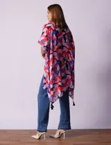 Kimono tejido con estampado floral multicolor y terminación de ruedo con borlas verdes.