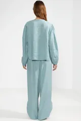 Pantalón celeste de lino italiano, de pierna ancha, con cintura elástica ajustable con cordón, bolsillos laterales y cortes redondeados en los laterales.