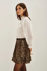 Falda corta plisada con estampado animal print de leopardo, con detalle de volado en el ruedo y cintura elástica.