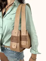 Bolso tipo baguette de cuero genuino color marrón claro, con dos compartimentos frontales con solapa y un parche de gamuza con el logo de un búho grabado. Posee una correa ancha de cuero ajustable.