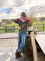 Sweater de punto color crema con diseño geométrico en tonos marrones, naranjas, verdes y grises en el pecho y las mangas. Confeccionado con lana y cuero, con detalles tejidos y bordados a mano.