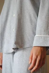 Conjunto de pijama de algodón gris con estampado geométrico blanco, compuesto por una camisa de manga larga con botones y un pantalón largo con elástico en la cintura.