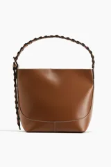 Cartera tipo hobo de diseño estructurado en color marrón, con costuras visibles en contraste y correa de hombro trenzada en tonos marrón y negro con hebilla metálica lateral.