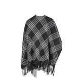 Poncho abierto con diseño de cuadros escoceses en tonos negro, gris y blanco. Presenta bordes con flecos largos y una caída fluida sobre los hombros.