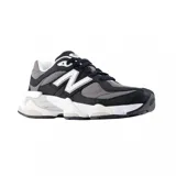 Championes urbanos New Balance modelo 9060, con diseño robusto y moderno. Presentan una combinación de colores negro, gris y blanco, con paneles de malla y superposiciones de gamuza. Incluyen el logo 'N' característico en los laterales y una suela gruesa con tecnología de amortiguación.
