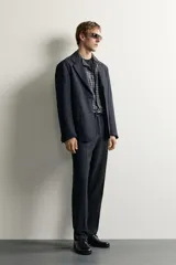 Blazer de corte relaxed fit con cuello de solapas de muesca y cierre frontal de un botón. Cuenta con bolsillos de plastrón en la cadera y mangas largas.