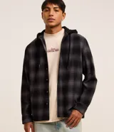 Camisa de franela a cuadros en tonos gris y negro, de corte comfort, con mangas largas, cierre frontal abotonado y capucha incorporada en color negro con cordón de ajuste.