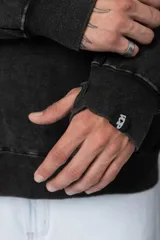 Buzo canguro de frisa gruesa con capucha, diseño oversize y acabado con efecto gastado. Presenta recortes horizontales en el frente y puños con elástico.