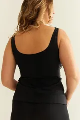 Camiseta tankini negra con estampado abstracto en blanco y beige, con nudo para regular el escote y breteles anchos. Incluye bolsillo interno en el busto para colocar copa removible o prótesis externa.