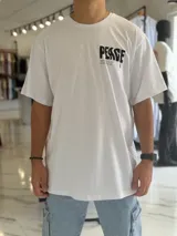 Remera oversize blanca de manga corta, con gran estampado negro en la espalda con la palabra 'Peace' y símbolos gráficos.