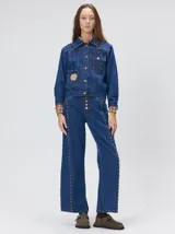 Campera de jean estilo cazadora con corte crop, cierre frontal con botones metálicos, bolsillos delanteros con apliques, bordados y detalles de tachas metálicas en el pecho.