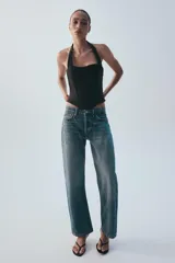 Jeans rectos de tiro medio en denim negro con efecto lavado. Presenta diseño de cinco bolsillos, trabillas para cinto y bajo con vuelta marcada. Cierre frontal con botones metálicos ocultos.