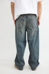 Jean de corte holgado y tiro medio, confeccionado en denim de algodón con lavado oscuro y efecto desgastado vintage. Presenta pierna ancha y diseño de cinco bolsillos.