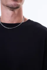 Buzo de manga larga con textura tipo waffle, cuello redondo y corte holgado.