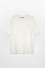 Remera color crudo de algodón con estampado en la espalda que incluye una pelota de tenis, el texto "YOU JUST GOT SERVED", "PASTICHE", "1984" y "BACK SPIN AGAIN & PUS".