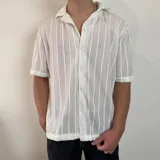Camisa de manga corta confeccionada en tejido de crochet con diseño de rayas verticales, cuello solapa y cierre frontal con botones.