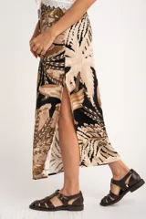 Falda larga con estampado de hojas en tonos beige, marrón y negro, con cintura elastizada y cordón ajustable.