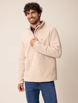 Sweater de polar color beige, con cuello alto y cierre frontal parcial. Presenta un pequeño logo bordado en el pecho.