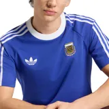 Remera de fútbol Adidas Originals de la selección argentina, de color azul con cuello redondo blanco y las clásicas tres tiras blancas en las mangas. Cuenta con el logo del trifolio de Adidas bordado en blanco y el escudo de la AFA en el pecho.