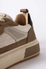 Championes urbanos de diseño moderno, combinando paneles de cuero texturizado en tono tostado y cuero liso en color crema. Presenta una suela de plataforma robusta en tono crema con un detalle en bloque tostado en el talón y un contrafuerte oscuro.