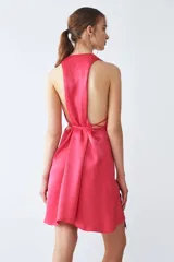 Vestido midi fucsia de tejido sastrero fino y liso con leve brillo, escote en V, tiras para ajustar en la cintura, volado asimétrico en el ruedo y espalda descubierta.