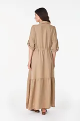 Vestido camisero largo de lino italiano color celeste, de corte relajado, con mangas caídas, jareta ajustable en la cintura, cierre frontal de botones y bajo con volado fruncido.