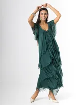Vestido largo de seda italiana color verde oscuro, con capas escalonadas con flecos, escote en V con detalle de paillettes y mangas cortas fluidas.