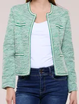 Chaqueta de tweed liviano en color verde, con escote redondo, frente abierto y bolsillos simulados con detalles de pasamanería. Cuenta con mangas largas de corte recto.