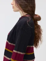 Sweater de punto cable con diseño a rayas horizontales en tonos marrón, amarillo y lila. Presenta cuello redondo acanalado, mangas largas con puños a juego y logo bordado en el pecho.