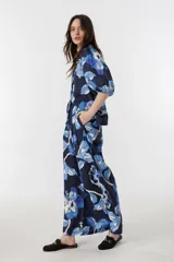Pantalón culotte de lino azul marino con estampado de flores azules y blancas, tiro alto, cintura con tablas, bolsillos laterales y cierre frontal.