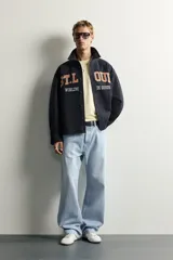 Jeans de denim de algodón en color azul con efecto desgastado, tiro medio y corte recto de ajuste holgado (loose fit). Cuenta con diseño clásico de cinco bolsillos y cierre frontal con cremallera y botón.