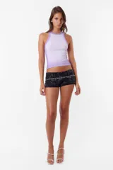 Microshort de gabardina de tiro bajo y corte slim fit. Presenta un diseño con costuras rojas a contratono, cierre metálico frontal y detalle de cadena metálica en la cintura. La prenda cuenta con un proceso de sobreteñido y lavado artesanal que le otorga un acabado único.