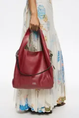 Bolso de mano grande Bimba y Lola modelo Paper, confeccionado en piel vacuna de color rojo. Presenta estructura blanda, asas de hombro fijas, tira lateral con mosquetón y detalle de logo metálico en la parte inferior.